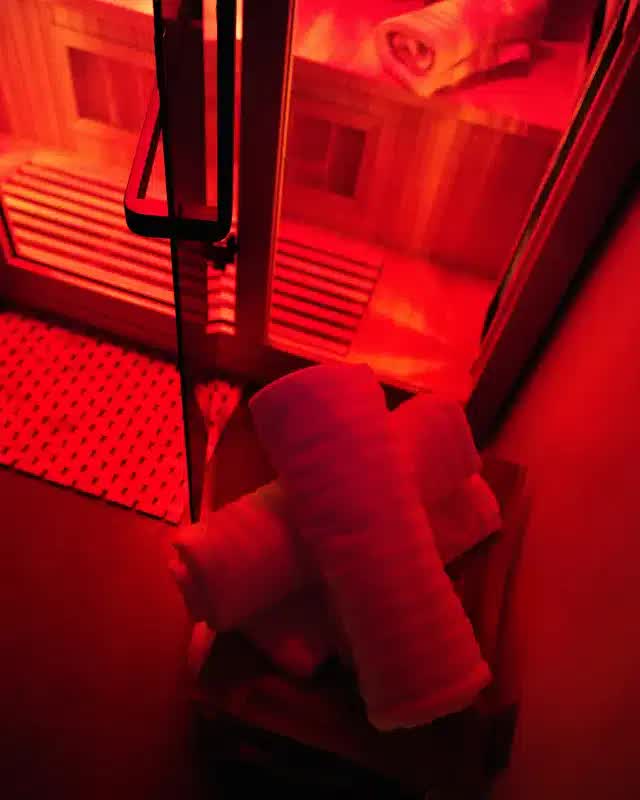 The infrared sauna at PEAKFIT. Studio glowing red, with rolled towels ready